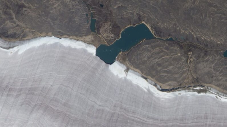 Mini lake meets snowy rim of Canada’s oldest ice mass โ Earth from space